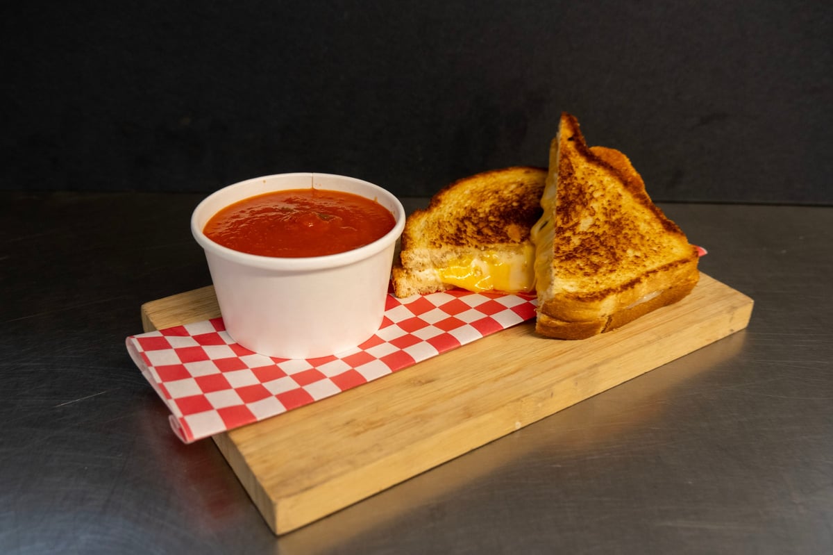 A cup of tomato soup and a full grilled cheese sandwich